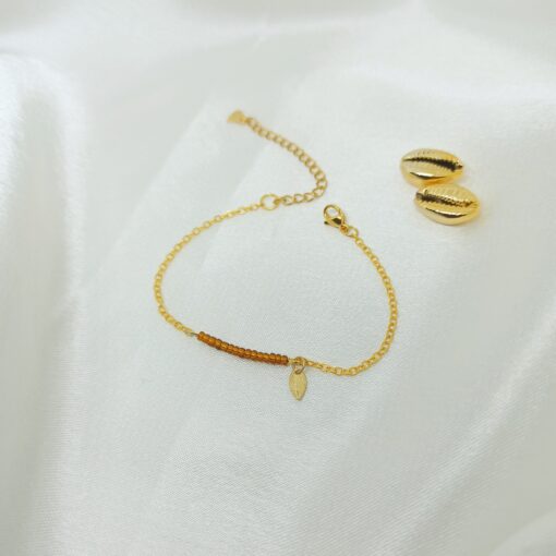 Photo d'un bracelet or et perles marron avec cauri en or
